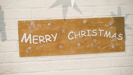 Brown sign with snowflakes and the inscription "Merry Christmas" hanging on a white brick wall