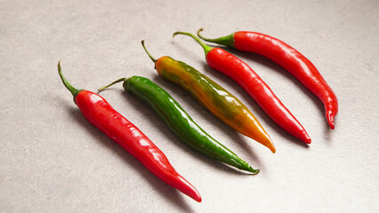 Red and green chili peppers on a gray background. Five pods of hot pepper