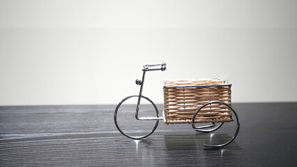 Metal stand for flowers "Bicycle" with an empty wicker planter on a wooden table