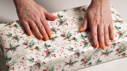 Obraz na płótnie Canvas The process of wrapping Christmas gifts with female hands, on a white background