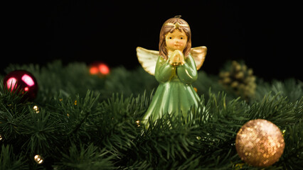 Christmas decoration with a toy in the form of a little angel standing on a branch of a coniferous...
