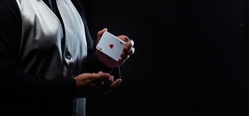 Magician illusionist showing performing card trick. Close up of hand and poker cards on black...