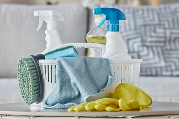Cleaning products, brush and basket on table in home living room for housekeeping. Hygiene, spring...