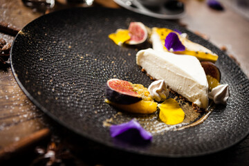 Cheesecake with passionfruit, fig and orange on a plate. Delicious healthy food closeup served for lunch on a table in modern gourmet cuisine restaurant - 552605913