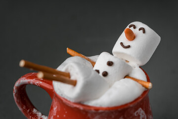 Marshmallow snowman taking hot tub in a red ceramic cup full of cocoa with milk foam. Christmas...