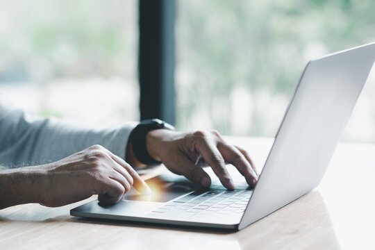 Man Uses His Finger To Press Button To Turn Off, Closed, Shut Down Laptop Computer Placed On Desk, Is Time To Finish Each Day Before Going Home For Saving Energy. After Saving All Data Business Work.