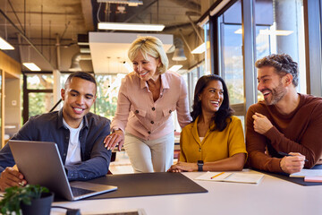 Multi-Cultural Business Team Meeting Around Laptop In Modern Office