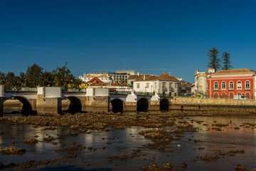 Widok na najstarszy most na rzece Gilao w miasteczku Tavira, Portugalia. Fragment nabrzeża, piękny słoneczny dzień.  - obrazy, fototapety, plakaty