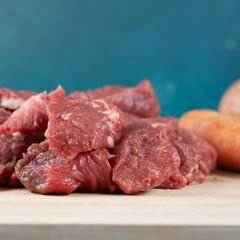 Close up of some Raw beef cut up into small cubes  on a bamboo cutting board