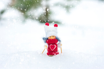 Girl skier toy in scarf and knitted hat skiing Elf toy on skis in snowy landscape New year, Merry Christmas greeting card winter Happy New Year card Hello December, January, February