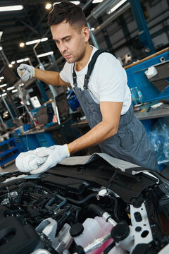 Portrait Of Mechanic Checking Quality Of Engine Oil