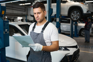 Mechanic checking car documents during car repiar