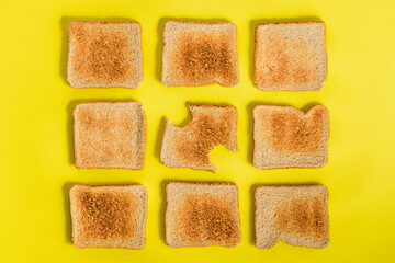 Gray plate with slice of toasted bread and several slices of toasted bread scattered on yellow background