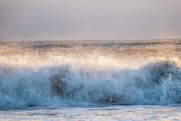Naklejka na ściany i meble Waves crashing onto Alnmouth Beach, Northumberland, at sunrise.