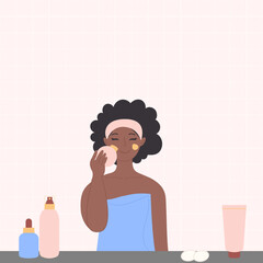 A black African-American woman is washing her face with cosmetics in the bathroom.