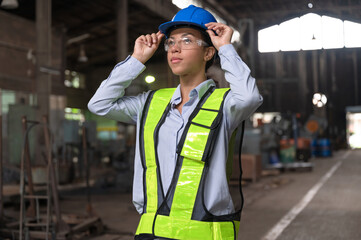 Portrait beautiful and confident Latin America woman engineer touching helmet at factory	