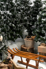 Wooden sled for snow against the background of Christmas trees and gifts. Christmas composition