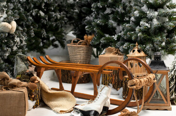 Wooden sled for snow against the background of Christmas trees and gifts. Christmas composition