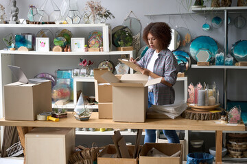 Female with laptop arranging souvenirs in own store
