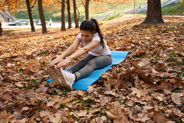 Woman stretching on a blue carimate in a city park