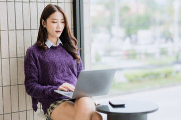 Pretty Asian woman using laptop in coffee shop