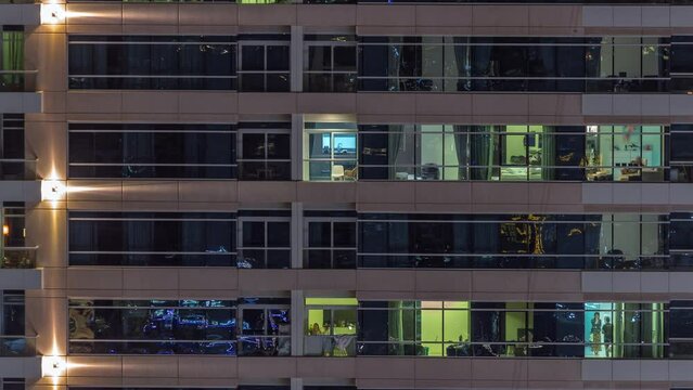 Flat night panorama of multicolor light in windows of multistory buildings aerial timelapse. Illuminated facade on skyscraper in a big city
