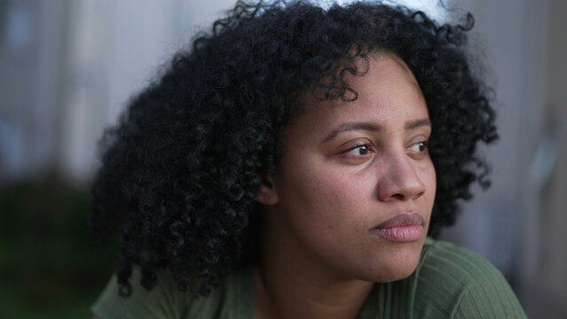 One contemplative young black woman closeup face. Pensive Brazilian adult girl stands outdoors in contemplation. Thoughtful South American female person
