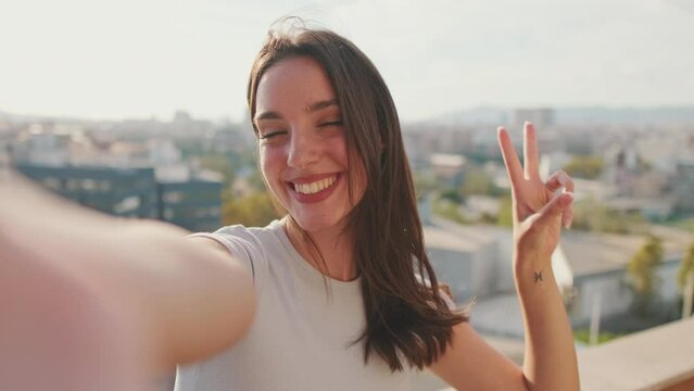 Close-up of young woman taking selfie hand peace sign while standing on balcony
