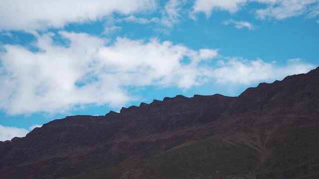 4K shot of clouds moving above the mountains as seen from Keylong in Lahaul and Spiti district at Himachal Pradesh, India. Clouds above the mountain peaks of Keylong. Nature Background.	
