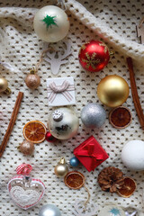 Fototapeta na wymiar Various colorful Christmas ornaments, small presents and seasonal spices on white knitted blanket. Top view.
