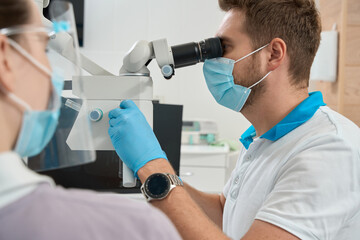 Experienced stomatologist adjusting optical instrument for dental work