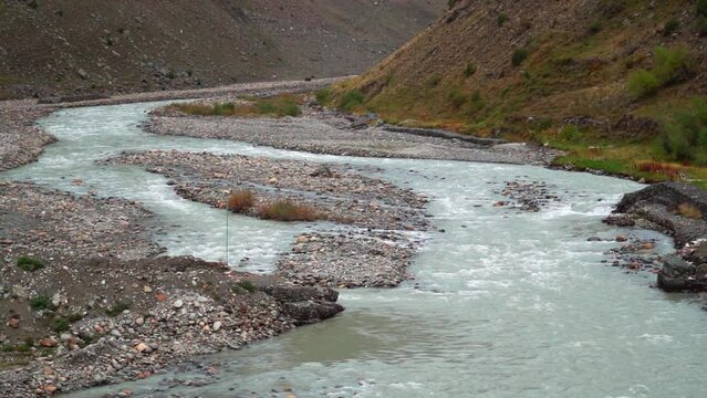 Handheld shot of the Bhaga River flowing under the Barsi Bridge as seen from above the bridge at Darcha in Himachal Pradesh, India. River flowing under the bridge. Natural river background.	