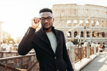 an african boy on holiday at the colosseum in a coat.