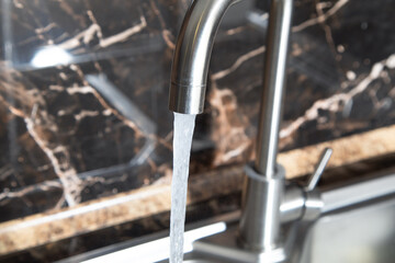 Obraz premium Water flows from the kitchen tap.