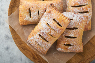 Hand pies. Mini puff pastry or hand pies stuffed with apple and sprinkle sugar powder in wooden plate. Homemade pie snack with crust for breakfast rustic photo.  Copy space. © kasia2003