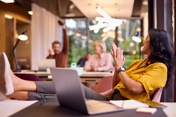 Mature Businesswoman With Feet On Desk In Office Throwing Small American Football