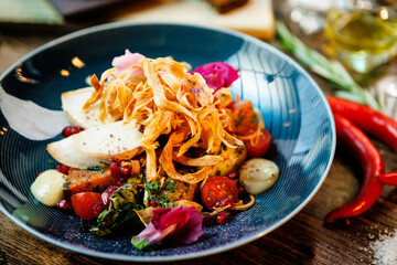 Warm salad with chicken. Almond potato, mini romaine lettuce, carrot, cherry tomato, pesto, black root chips, caramelized walnut, beet balsamic. Food closeup served for lunch in modern restaurant