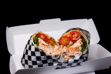 Mexican fast food. chicken burritos with tomatoes cherry rice and vegetables packed in paper box
