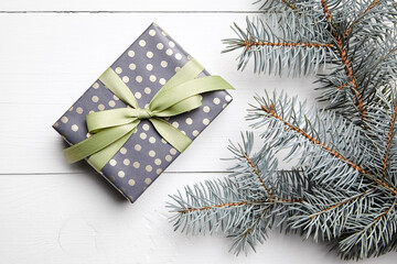 Christmas gift box and green fir tree branch on white wooden background, top view, flat lay. Winter...