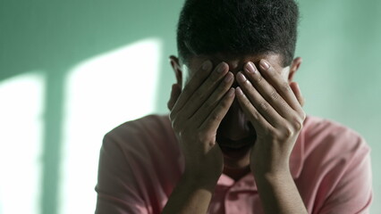 Desperate young man feeling hopeless and despair. A hispanic South American person crying covering face with hand 2