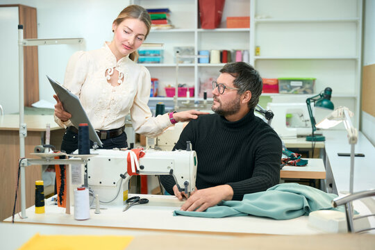 Beautiful woman stands at the table with a sewing machine