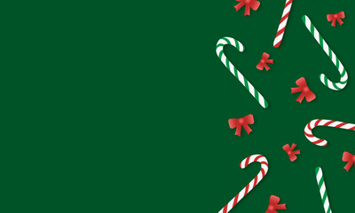 Green background with striped red and green candy canes and red bows with copy space