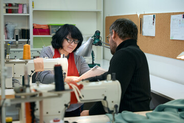 Tailors, a man and a woman, are considering working sketches