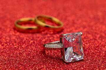 Will you marry me. Engagement ring and two wedding rings on red glitter background. Engagement marriage proposal wedding concept. St. Valentine's Day postcard. Banner on valentines day. Copy space
