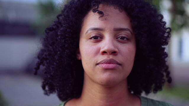 A Brazilian black young woman portrait face closeup standing outside looking at camera. African American adult girl female person