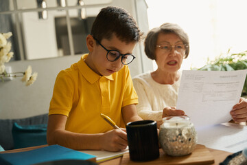 Old woman helping child to study during quarantine