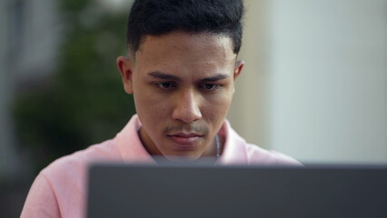 One young hispanic man closeup face looking at computer laptop outside