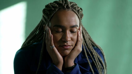 One pensive young black woman in contemplation. Thoughtful African American pensive adult girl with dreadlocks closeup face