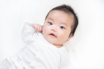 カメラ目線の笑顔でポーズをする生後2か月の赤ちゃん