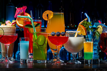Set of coctails on bar counter in a restaurant, pub. Collection of fresh juice alcoholic drinks. Cooler beverage at nightclub on dark background